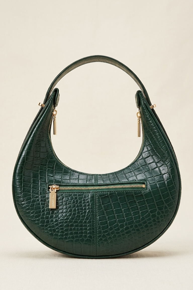 Green crocodile-patterned handbag with gold zippers on a beige background