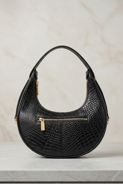 Black handbag with gold accents on a light gray background