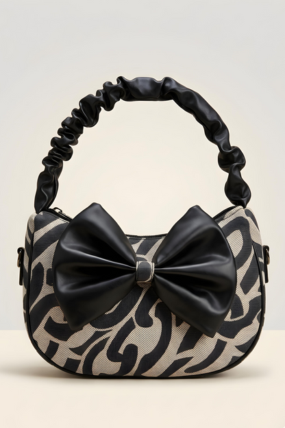 Handbag with black and beige pattern and a large bow on a light gray background